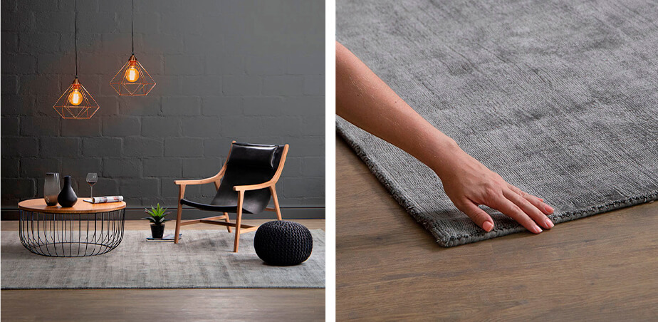 Black leather, wood armchair and round black metal and wooden coffee table on grey carpet with two geometric copper metal pendants hanging above coffee table against grey back wall and image of lady's hand touching grey carpet